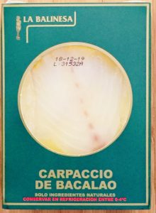 Envase de carpaccio de bacalao marca La Balinesa de 150 gramos. Se puede ver el producto a través de una ventana circular. Forma natural y saludable de bacalao.