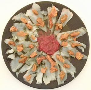 Plato de carpaccio de bacalao con huevas de erizo de mar y tomate triturado.