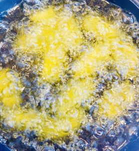 Croqueta de bacalao con piñones congelada recién sumergida en aceite de oliva virgen extra.